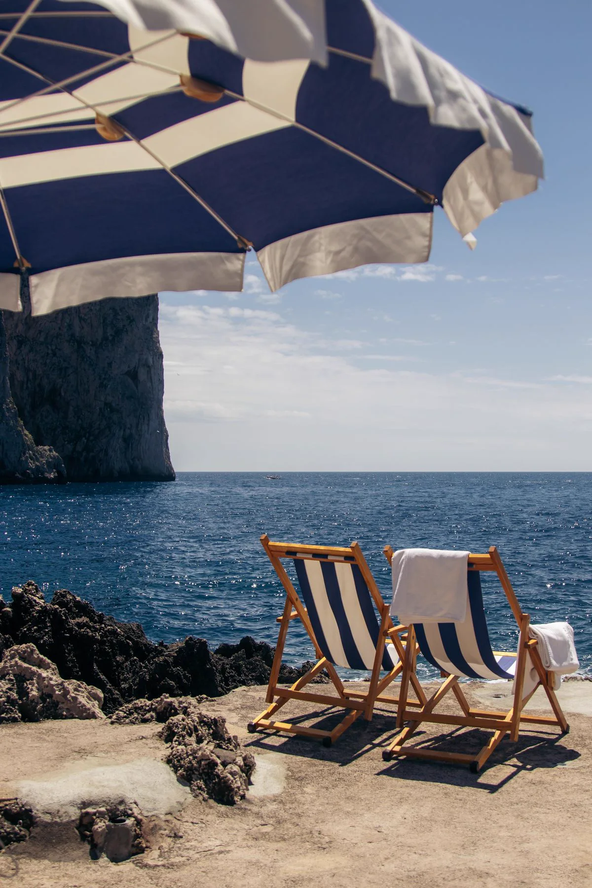 Cadeiras de praia sob guarda-sol listrado diante do mar de Capri, roteiro personalizado em Capri, Itália